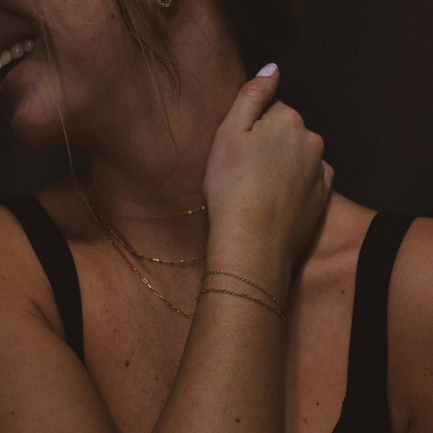 Layered delicate bracelets and necklaces with a dark top