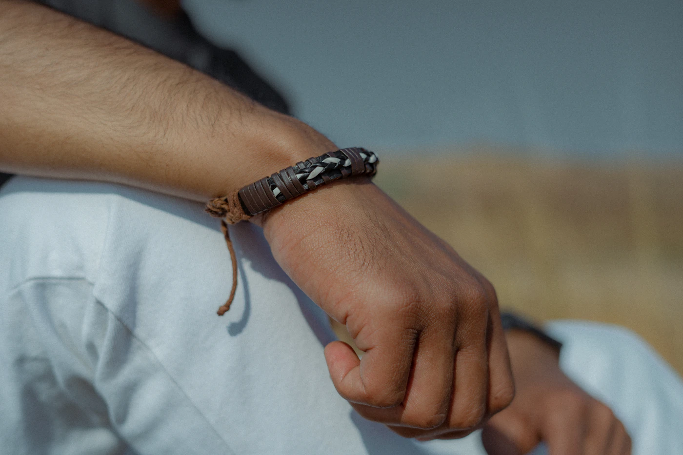 Beaded bracelet on a wrist resting against white trousers