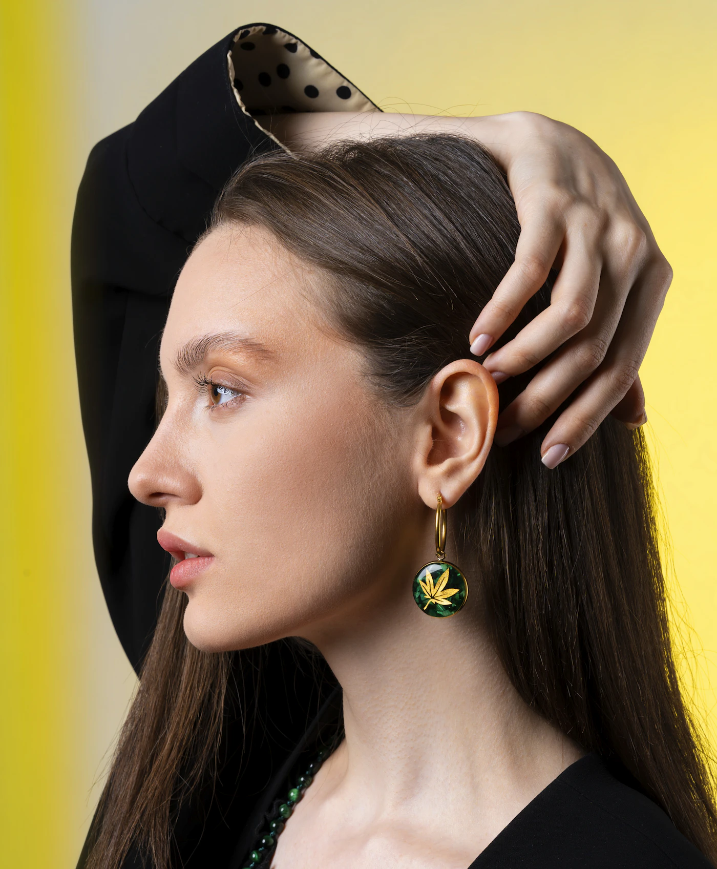 Woman adjusting her hair to show a green drop earring