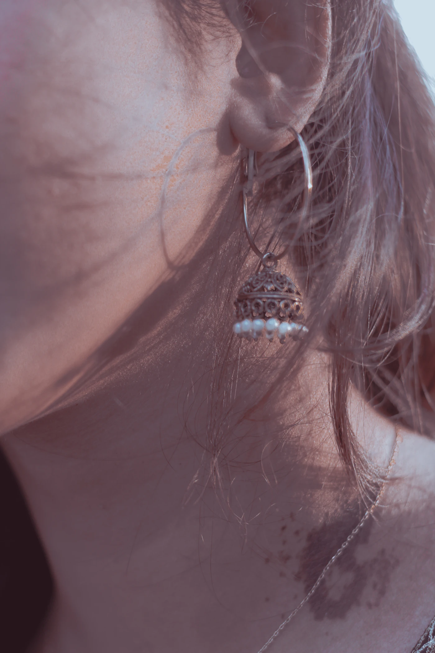 Close-up of a dangling earring beside loose hair