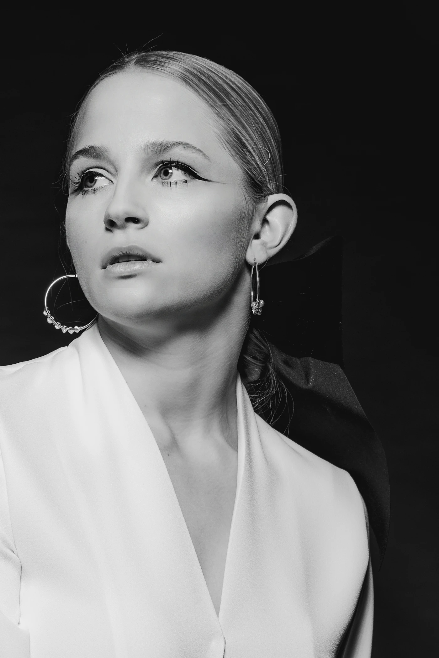 Woman wearing large hoop earrings with a white blouse