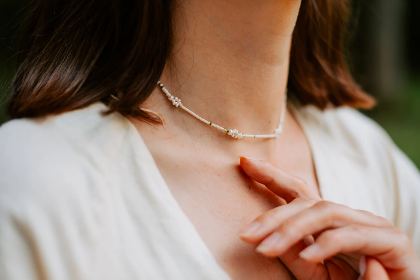 Woman in a white blouse wearing a delicate necklace in daylight