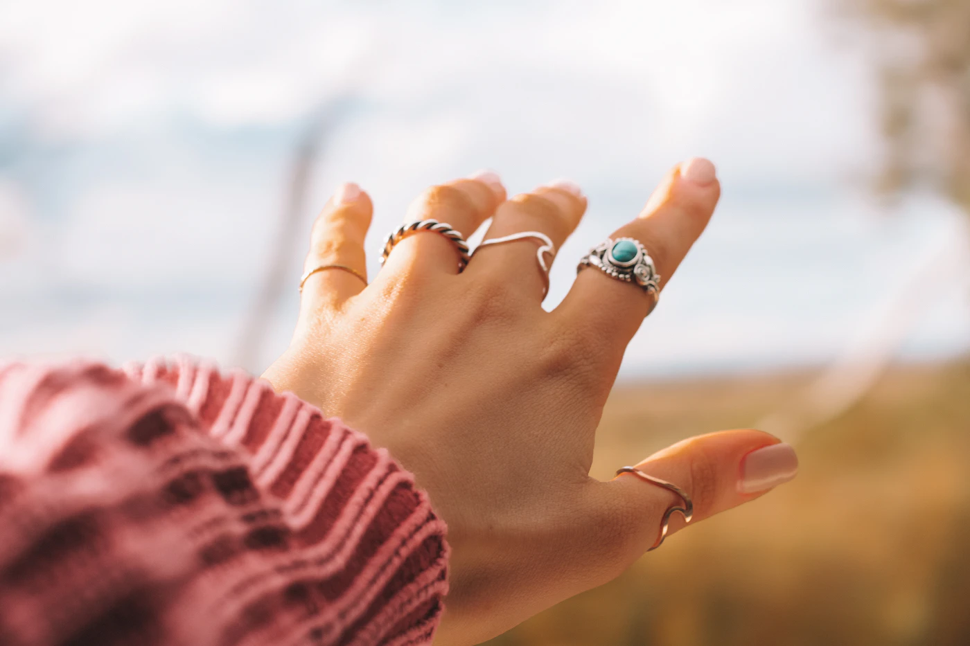 Hand wearing several rings held toward the sky during a road trip