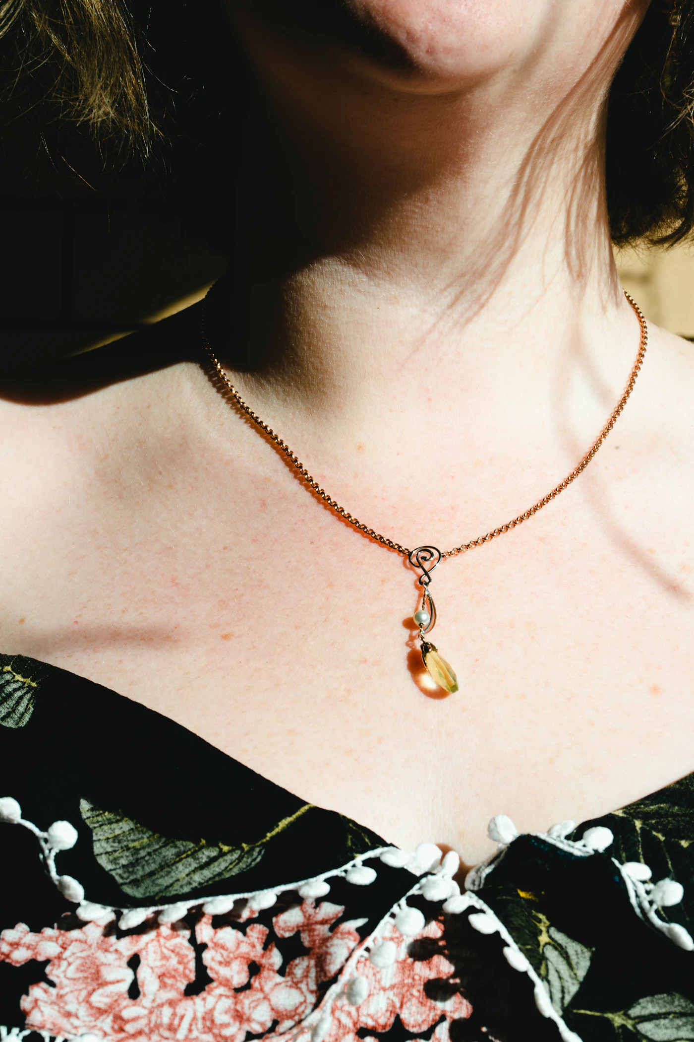 Gemstone pendant worn with a floral neckline