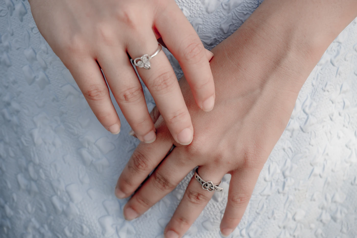 Close-up of hands wearing several rings with a light outfit